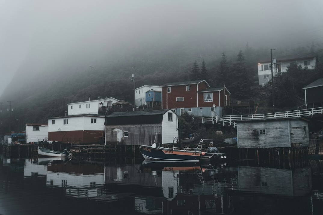 Foggy morning in a small Danish fishing harbour with boats and old houses